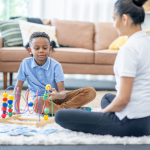 A Board Certified Behavior Analyst providing ABA therapy to a child using a colorful educational toy during a one-on-one session at The Buddy Center in Greenville, SC.